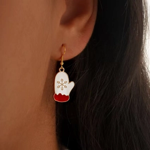 Detail shot of a festive white glove earring with red cuff and golden snowflake pattern