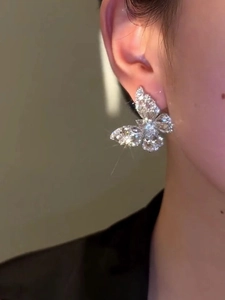 Close-up of sparkling butterfly earrings with ice zircon insets on a female model