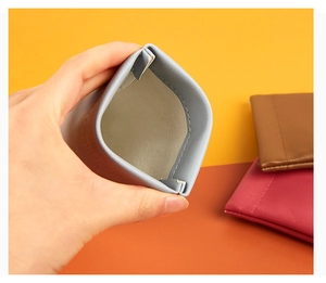 Detail of squeeze-to-open leather eyewear pouch with automatic spring closure feature