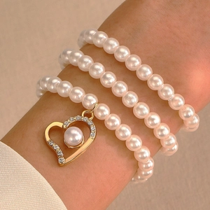 Bracciale multistrato di perle con ciondolo a cuore dorato e dettagli scintillanti in zircone