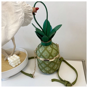 Detail of green pineapple-shaped crossbody bag with gold rivets and chain strap