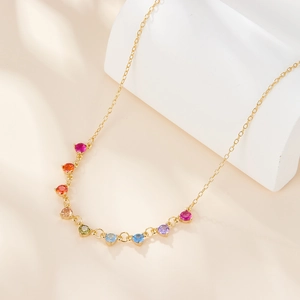 Close-up of gold s925 silver necklace with vibrant colorful zircon stones on stone base