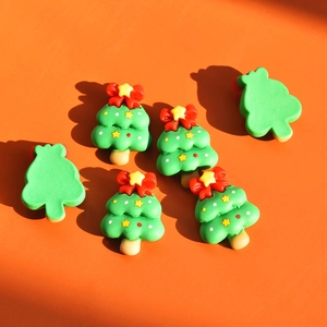 Detailed close-up of green resin Christmas tree charms with red bows for DIY crafts