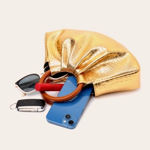 Detail of gold crocodile embossed bag showing storage capacity with wood handle