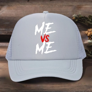 Gray mesh trucker hat with ME VS ME print and adjustable strap on a wooden surface