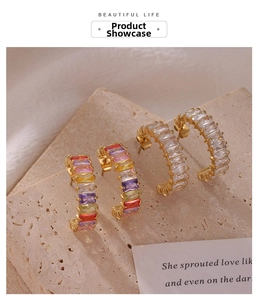Détail macro de boucles d'oreilles C dorées avec oxydes de zirconium colorés taille degrés