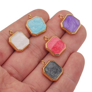 Hand holding five colorful hexagonal stainless steel pendants with marble texture
