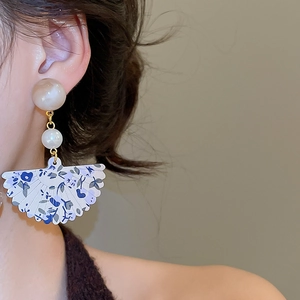 Detail view of fan-shaped resin drop earrings with blue floral pattern and pearl