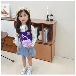 Detail of purple woven mini bag with pearl handle and cute charms on a girl
