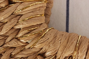Macro shot of fine straw weaving texture with gold metallic thread on a beach bag