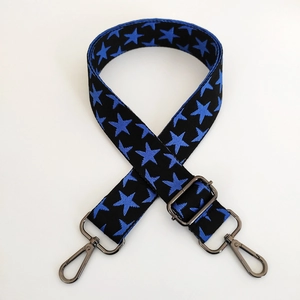 Close-up of black knit bag strap with blue stars and gunmetal adjustable buckles