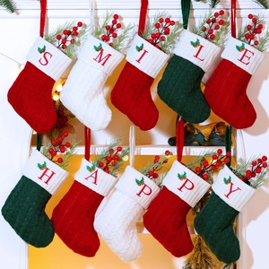 Close-up of knitted Christmas stockings with red letter embroidery and classic textures