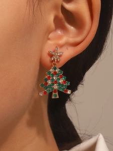 Detail of glittering Christmas tree earrings with colorful rhinestones on female ear