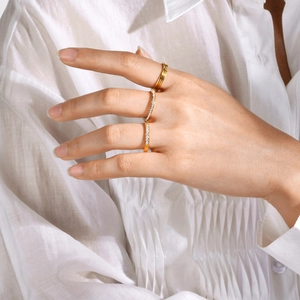 Detailed close-up of a stacked gold ring set with micro-pave zircon on a model's hand