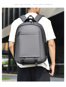 Modern grey backpack with front zipper pocket and side mesh pocket worn by a male model