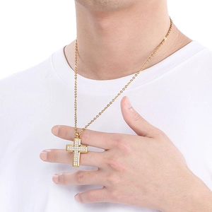 Detailed view of a gold cross pendant necklace with clear zircons worn by a model