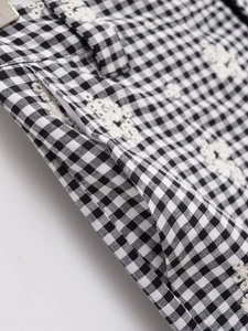 Détail du tissu vichy noir avec broderie florale délicate et poche latérale du pantalon