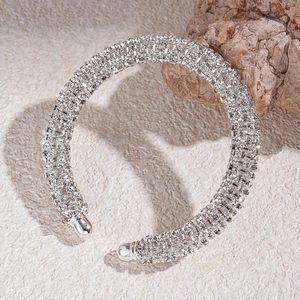Détail du bracelet ouvert argenté projetant une ombre en forme de cœur sur le sable