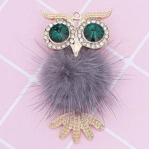 Detailed close-up of a sparkling owl pendant featuring a grey fur ball and green crystal eyes