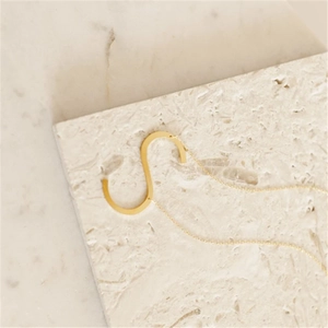 Elegant gold stainless steel necklace with letter S pendant on a textured stone base
