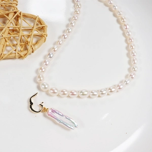 Detailed close-up of a white freshwater pearl necklace with baroque pendant and gold clasp