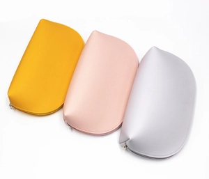 Close-up of three half-round PU leather makeup bags in yellow, pink and silver colors