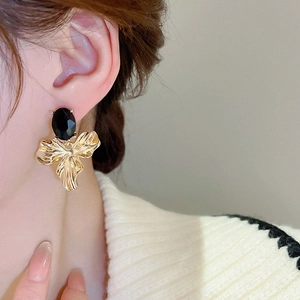 Detail of vintage flower earrings with black oval gem and gold pleated petals on model