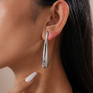 Macro side view of a glossy silver teardrop earring on model showing polished metal texture