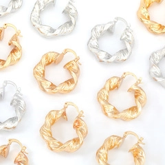Macro detail of twisted round earrings in polished gold and silver finishes