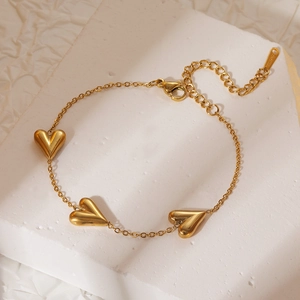 Minimalist gold stainless steel bracelet featuring three heart charms on stone base