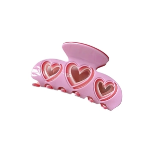 Pink Y2K style heart shaped hair claw clip with hollow design on white background