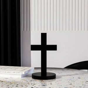 Decoración de cruz negra minimalista con base redonda en mesa de terrazo