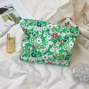 Flat lay of small green floral cosmetic bag with cotton fabric texture and brand label
