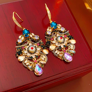 Detailed close-up of vintage baroque style earrings with colorful crystals on wood
