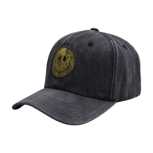 Detailed view of yellow sequin smiley face patch on a dark grey washed denim baseball cap