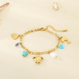 Détail du bracelet océan doré avec tortue, dauphin et turquoise sur une chaîne Figaro