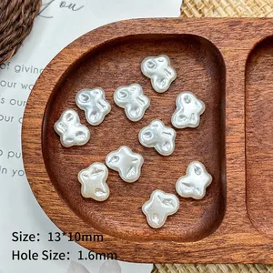 Detail of 13x10mm pearl white butterfly beads for DIY jewelry making on wooden tray