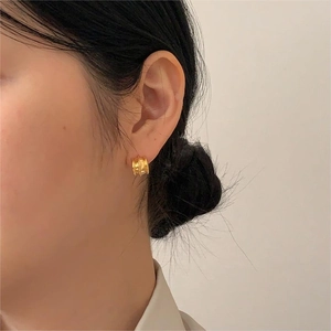 Close-up of a model wearing gold C-shaped ribbed earrings in 925 sterling silver