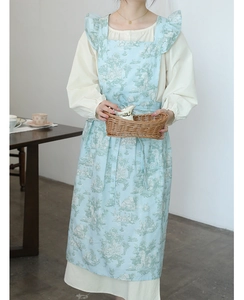Detail of light blue toile pattern floral apron with ruffled straps in a vintage style