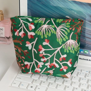 Trousse à maquillage fleurie verte sur clavier d'ordinateur portable et accessoires