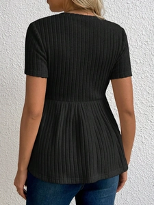 Detailaufnahme von schwarzem Umstandsoberteil mit Rippstrick-Textur und Schößchen-Saum