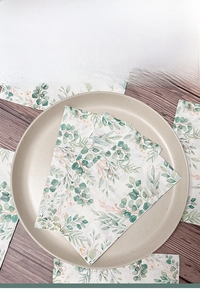 Close-up of rectangle paper napkins with green plant prints on a ceramic plate