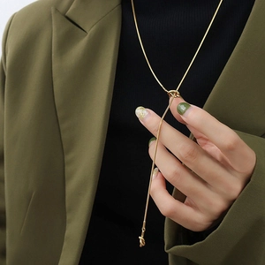 Detail of a long gold titanium steel knotted chain necklace worn with a green blazer