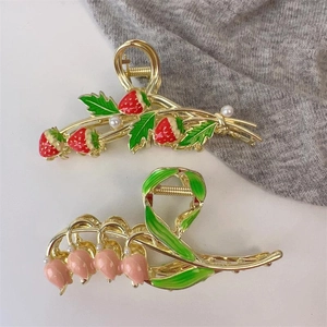Elegant strawberry and tulip hair claws with gold alloy base and pearls on white surface