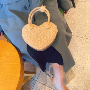 Detail of beige heart-shaped jelly bag with quilted pattern and single top handle