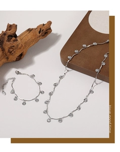Detailed view of silver sunburst pendant necklace and bracelet set on wooden background