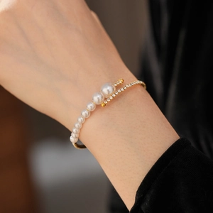Detail of a wrap-around gold cuff with layered pearls and pavé cubic zirconia accents