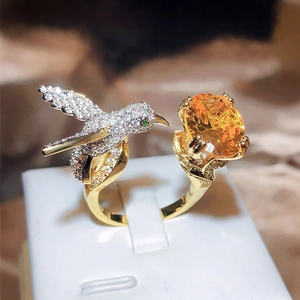 Detailed macro view of hummingbird ring with yellow gemstone and pavé crystal setting