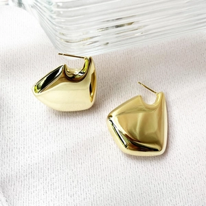 Detailed view of 18K gold plated U-shaped geometric earrings on white fabric