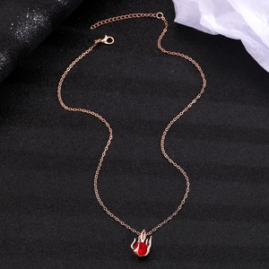 Macro detail of gothic rose gold necklace featuring a hand holding a red gemstone heart